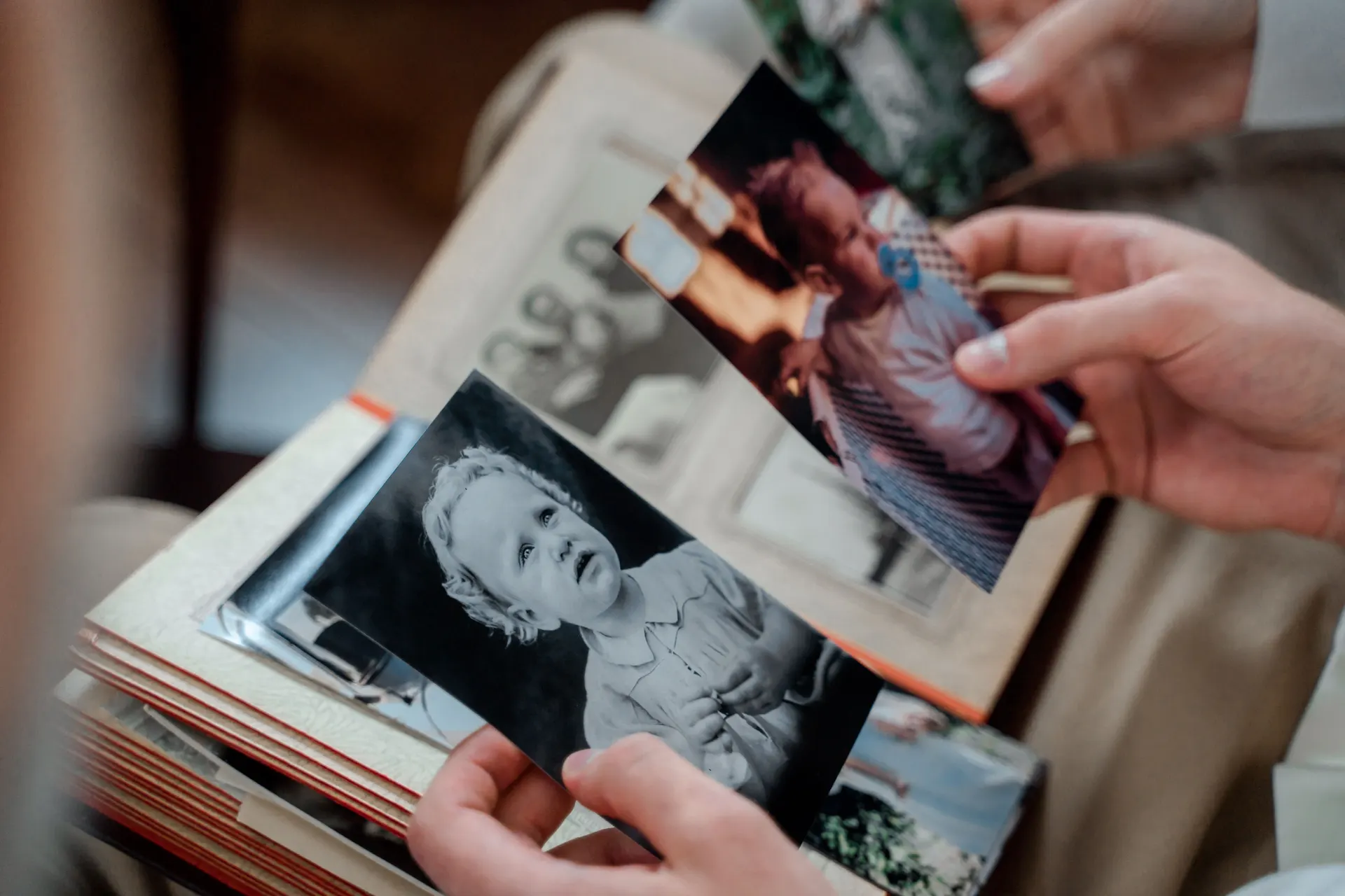 Hands holding an old photograph above a family album