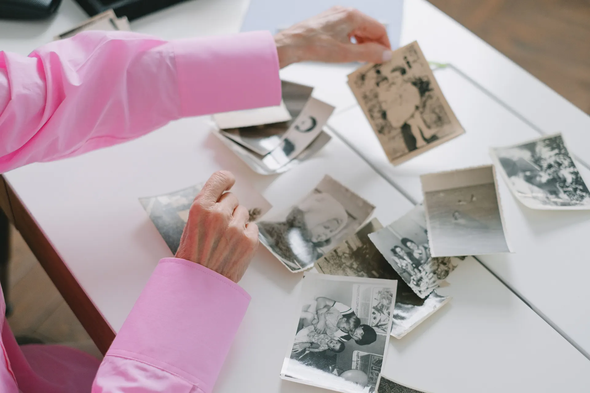 Hands sorting a table full of old black and white family photographs